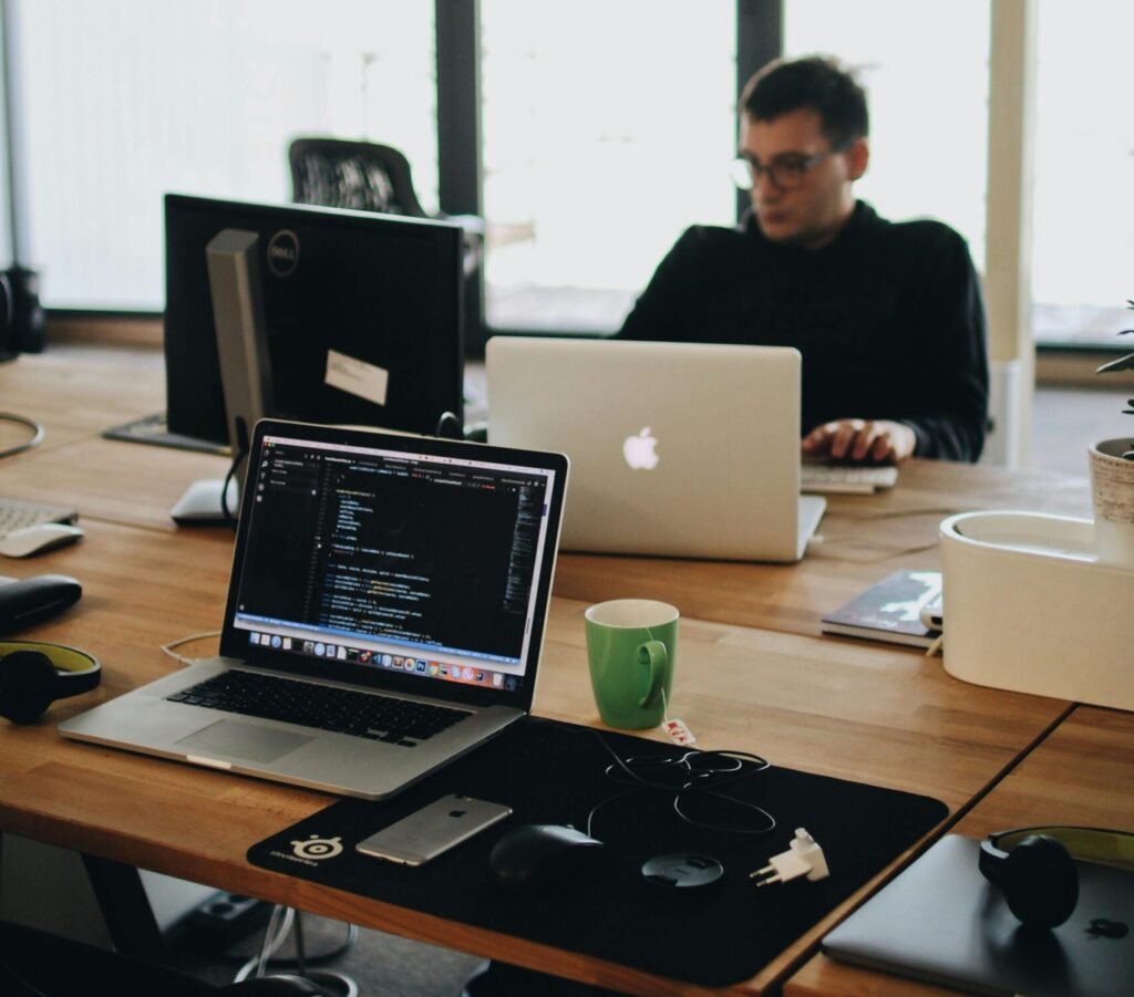 Man in Black Shirt Sits Behind Desk With Computers